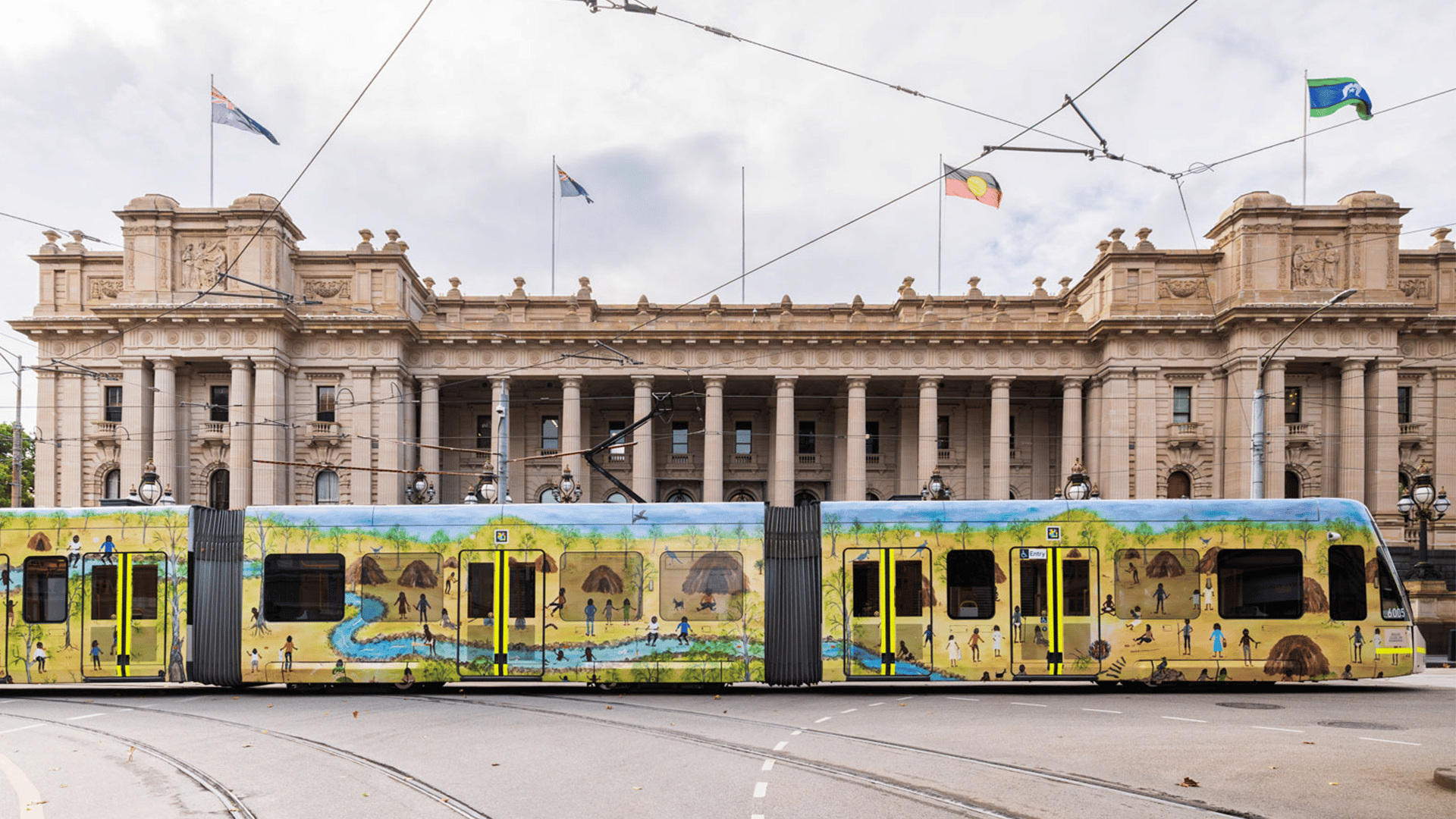 A tram in that is wrapped in a Marlene Gibson painting sitting out the front of Parliament House, an old Victorian era building.