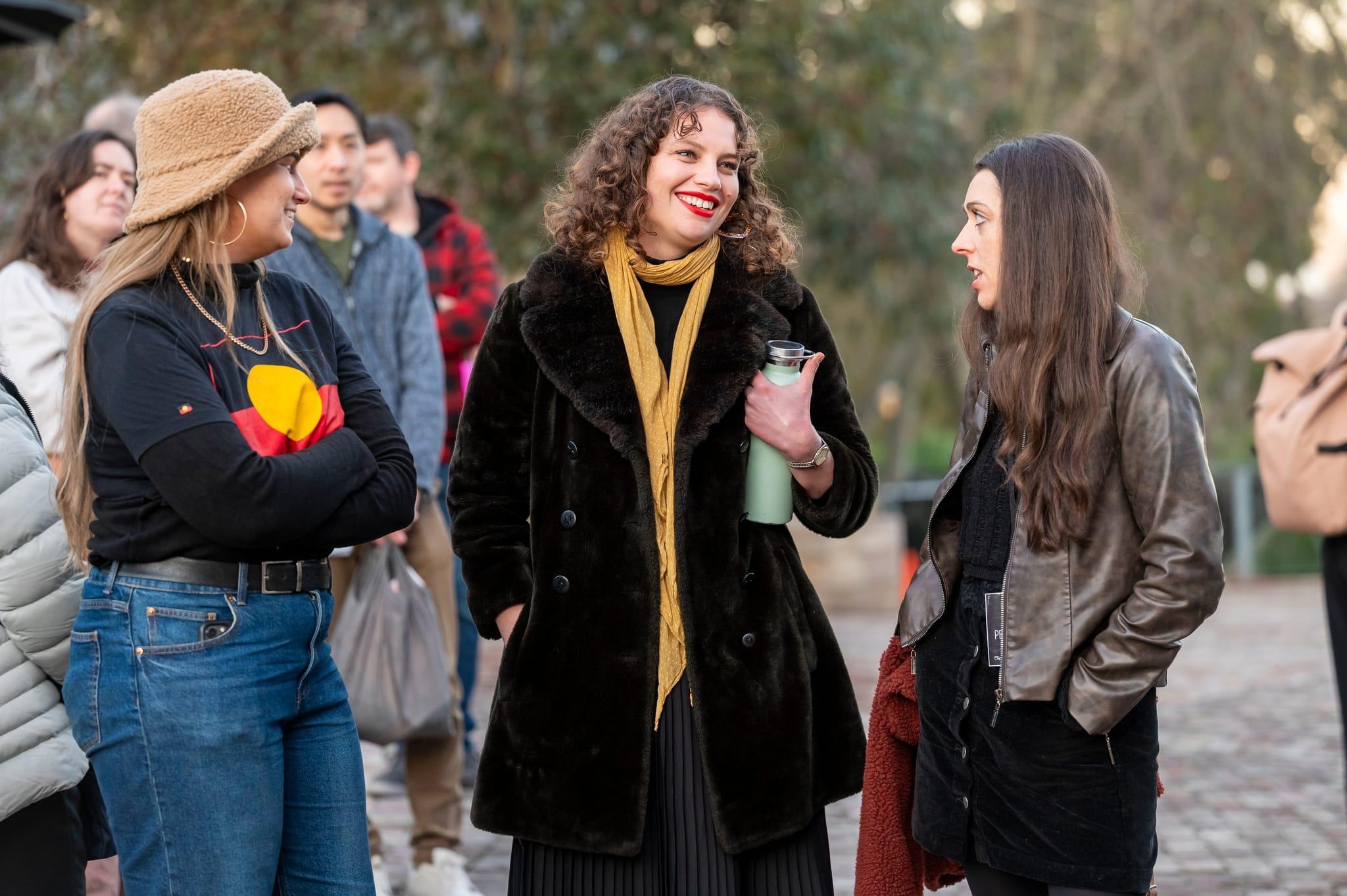Three woman talking to each other while enjoying an event at Fed Square.